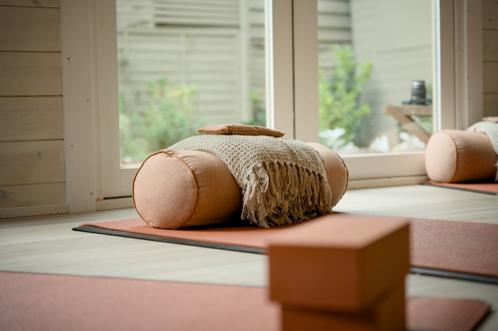 Bolster and blanket on a yoga mat by the window